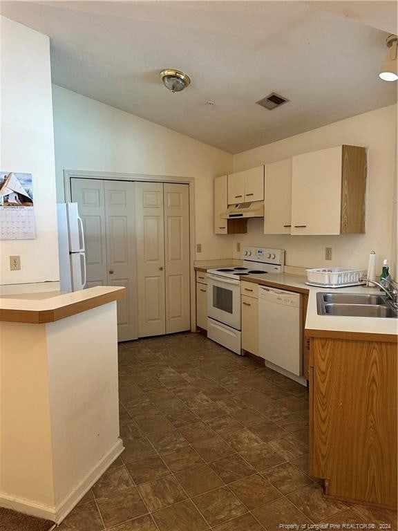 kitchen featuring dark tile floors, sink, white appliances, white cabinetry, and vaulted ceiling