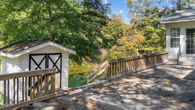 wooden terrace with a water view and a storage shed