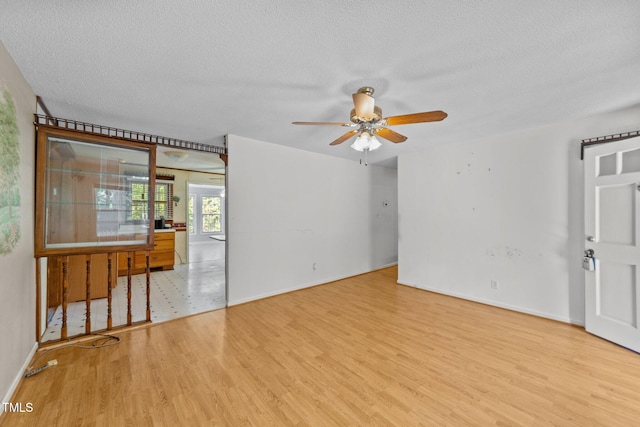 unfurnished room featuring ceiling fan, a textured ceiling, and light wood-type flooring