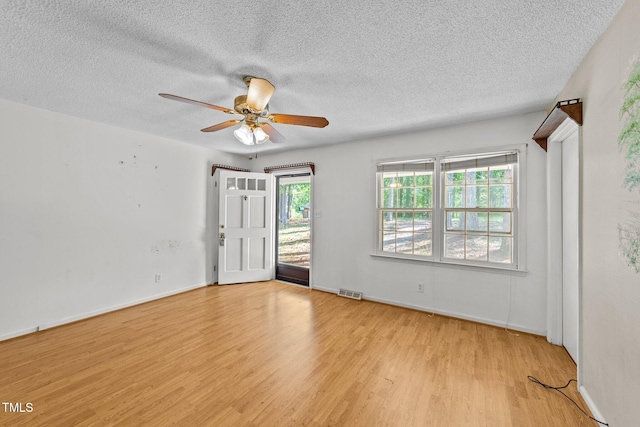 spare room featuring light hardwood / wood-style floors, a textured ceiling, and a healthy amount of sunlight