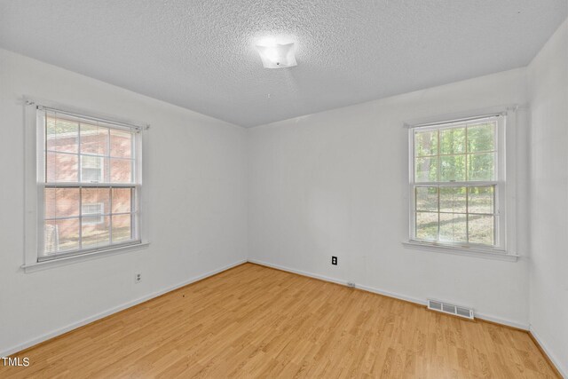 spare room featuring light hardwood / wood-style floors and a textured ceiling