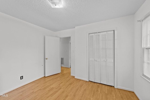 unfurnished bedroom with a textured ceiling, a closet, and light hardwood / wood-style flooring