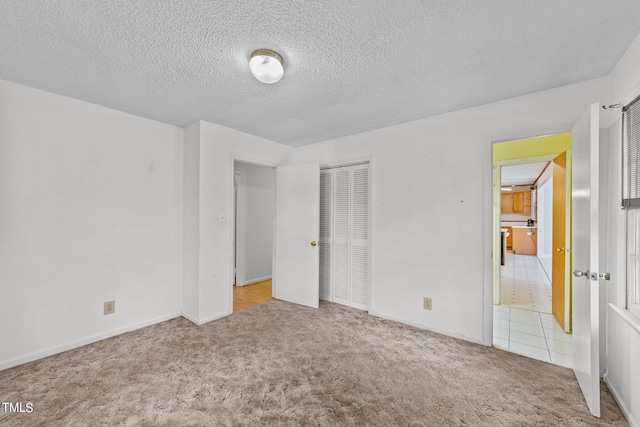 unfurnished bedroom with light colored carpet, a textured ceiling, and a closet