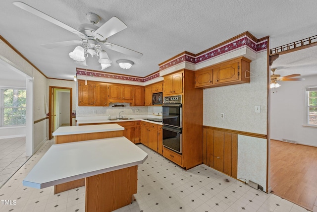 kitchen featuring a kitchen island, black appliances, sink, crown molding, and a textured ceiling