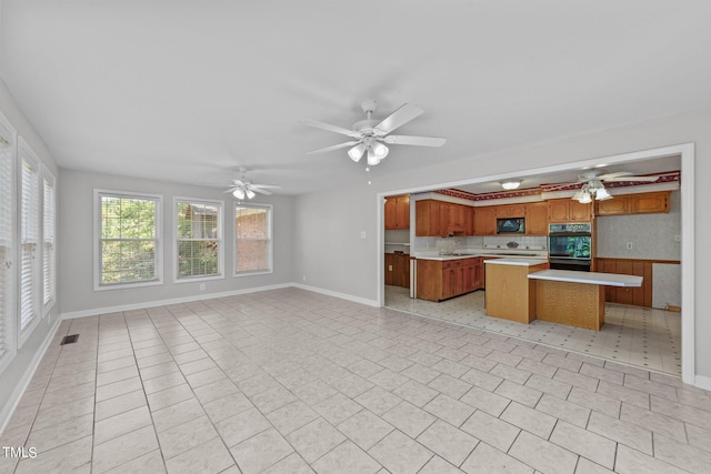 kitchen with black appliances, light tile patterned flooring, ceiling fan, and a center island