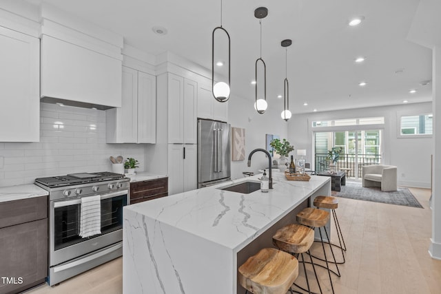 kitchen with light stone counters, appliances with stainless steel finishes, decorative backsplash, and a sink