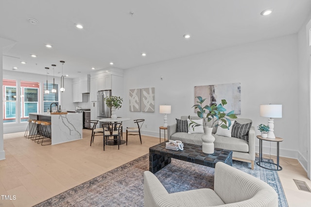 living room featuring recessed lighting, visible vents, light wood-style flooring, and baseboards