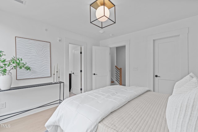 bedroom featuring a baseboard heating unit, visible vents, and wood finished floors