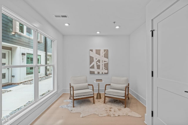 living area featuring baseboards, light wood-type flooring, visible vents, and recessed lighting