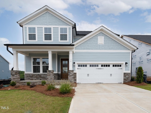 craftsman-style home with a garage, a front yard, and covered porch