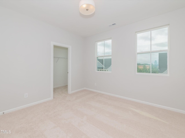 unfurnished bedroom with light colored carpet, a spacious closet, and a closet