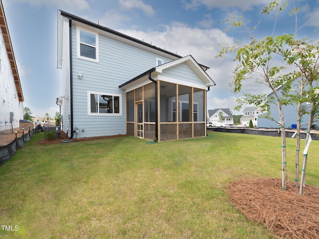 back of house with a sunroom and a lawn