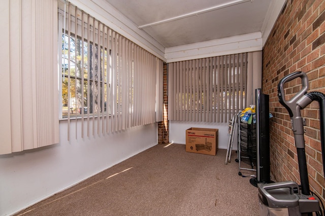 interior space with brick wall, dark colored carpet, and crown molding