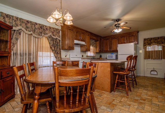 dining space with ceiling fan with notable chandelier, crown molding, and sink