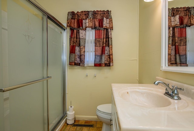 bathroom featuring a shower with door, vanity with extensive cabinet space, toilet, and tile floors