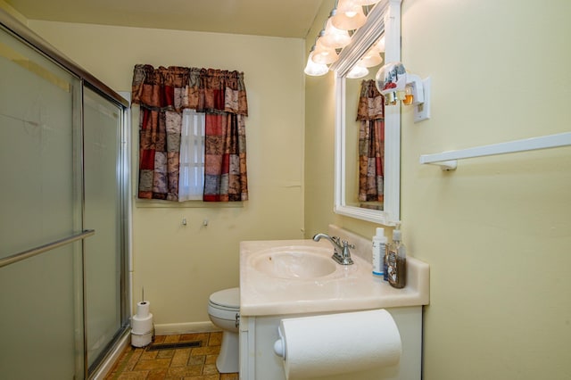 bathroom with vanity with extensive cabinet space, a shower with shower door, toilet, and tile floors