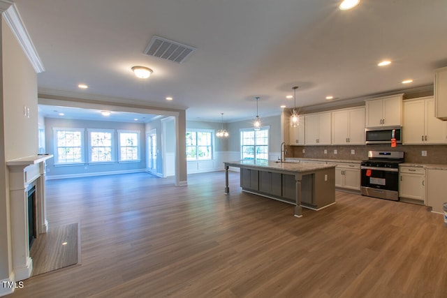 kitchen featuring sink, dark wood-type flooring, a kitchen island with sink, a breakfast bar area, and stainless steel appliances