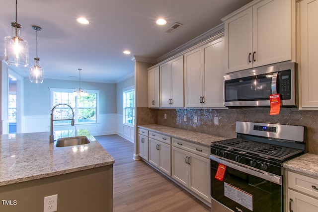 kitchen featuring appliances with stainless steel finishes, sink, light hardwood / wood-style flooring, and decorative backsplash