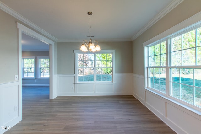 unfurnished dining area with a wealth of natural light, a notable chandelier, dark hardwood / wood-style flooring, and ornamental molding