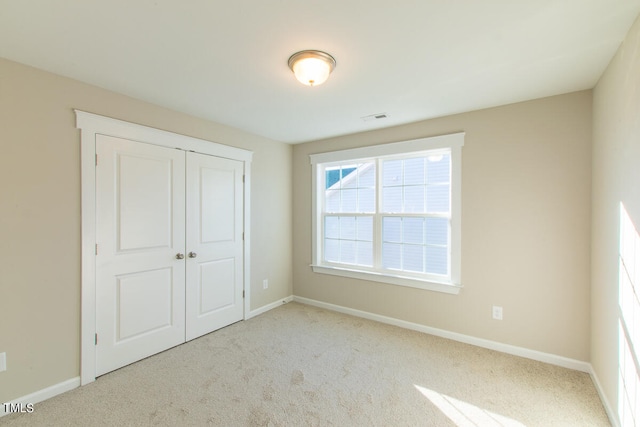 unfurnished bedroom featuring light carpet and a closet