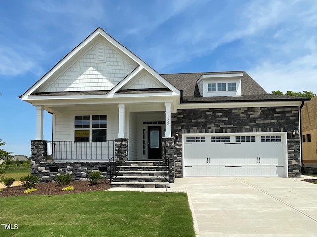 craftsman-style house with a front yard, a porch, and a garage