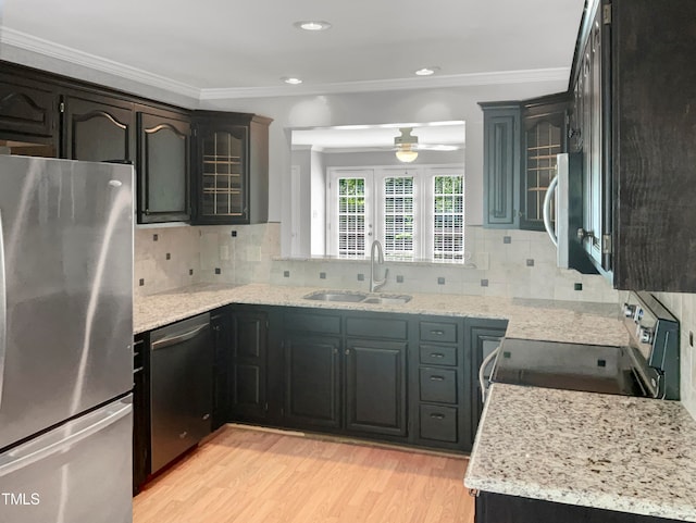 kitchen with light stone countertops, ceiling fan, stainless steel appliances, sink, and light wood-type flooring