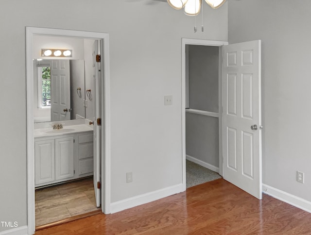 unfurnished bedroom featuring wood-type flooring, sink, and ensuite bathroom