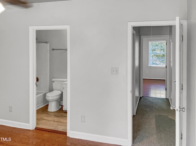 interior space with wood-type flooring, ceiling fan, and connected bathroom