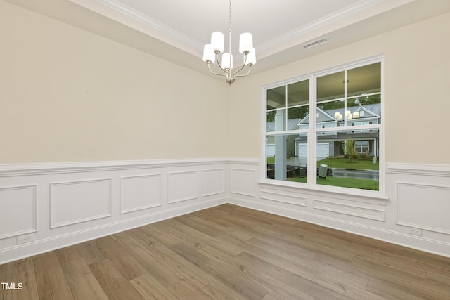 spare room featuring a chandelier, light hardwood / wood-style floors, and crown molding