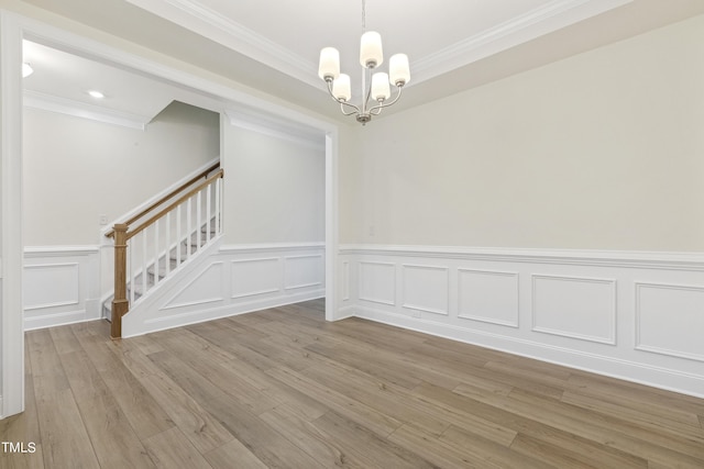 unfurnished dining area featuring ornamental molding, light hardwood / wood-style flooring, and a chandelier