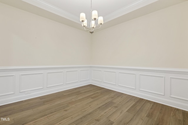 spare room featuring an inviting chandelier, hardwood / wood-style floors, and crown molding