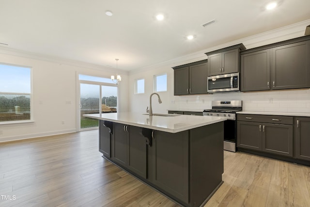 kitchen with stainless steel appliances, a center island with sink, sink, and light wood-type flooring