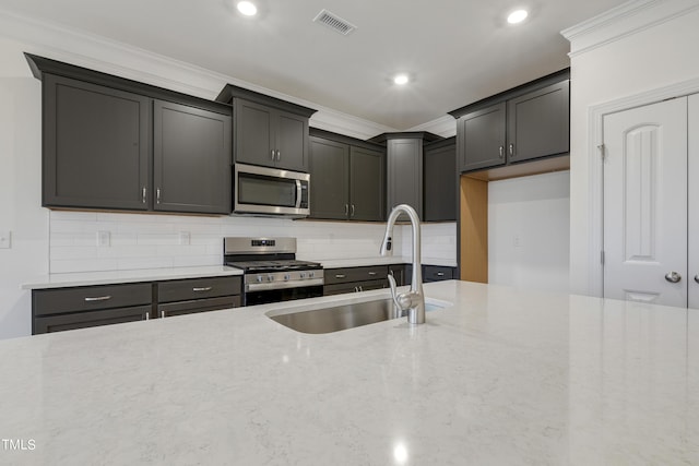 kitchen with light stone counters, stainless steel appliances, tasteful backsplash, ornamental molding, and sink