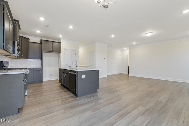 kitchen with appliances with stainless steel finishes, light hardwood / wood-style floors, sink, and a center island with sink