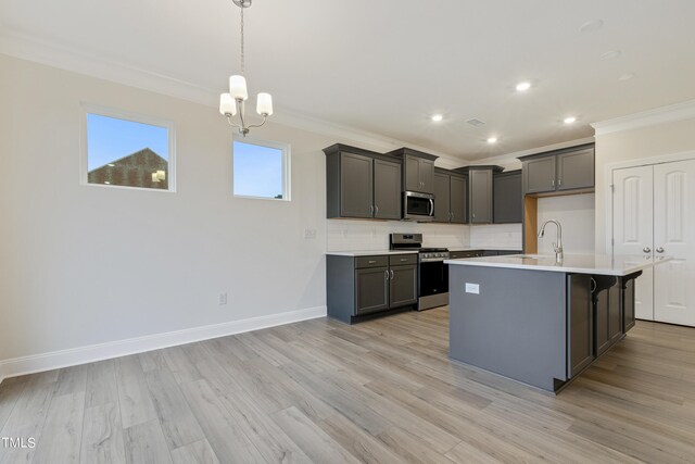 kitchen featuring stainless steel appliances, a notable chandelier, light hardwood / wood-style floors, a kitchen island with sink, and crown molding