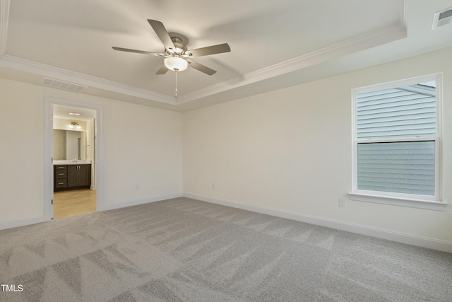 empty room with ornamental molding, light colored carpet, a raised ceiling, and ceiling fan