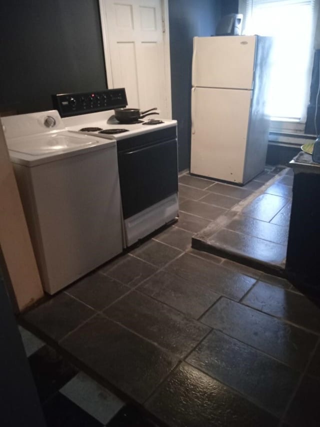 kitchen featuring white appliances, dark tile floors, tile countertops, and washer / clothes dryer