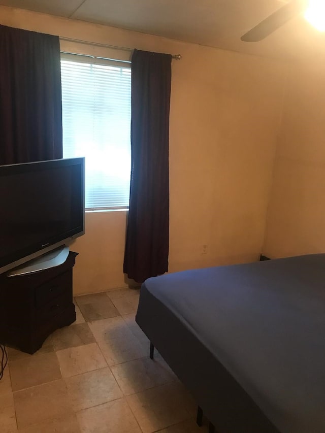 tiled bedroom with ceiling fan and multiple windows