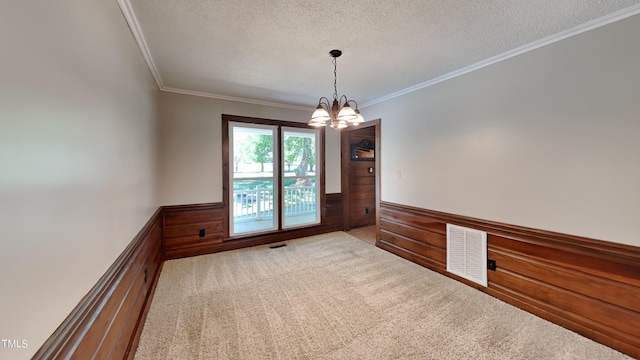 carpeted spare room featuring ornamental molding, a textured ceiling, and a notable chandelier