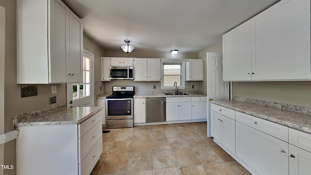 kitchen with white cabinetry, stainless steel appliances, light tile floors, and sink