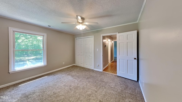 unfurnished bedroom featuring a closet, carpet floors, ornamental molding, ceiling fan, and a textured ceiling