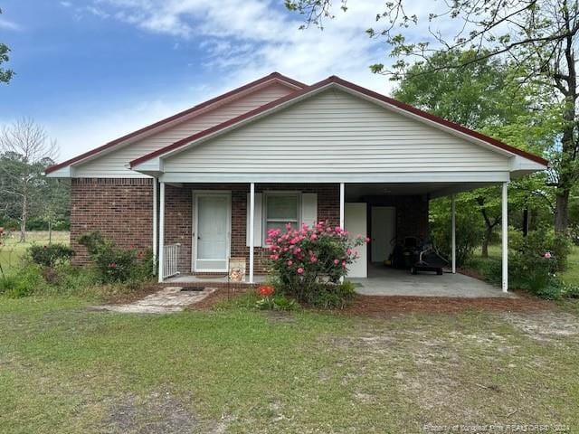 view of front of house with a front lawn, covered porch, and a carport