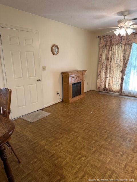 unfurnished living room featuring ceiling fan and dark parquet flooring