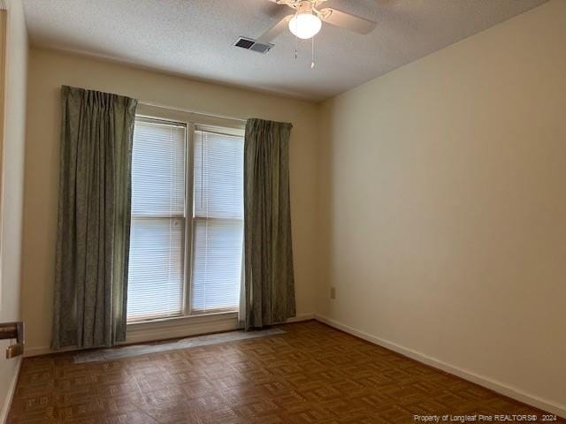 unfurnished room with ceiling fan, parquet floors, and a textured ceiling