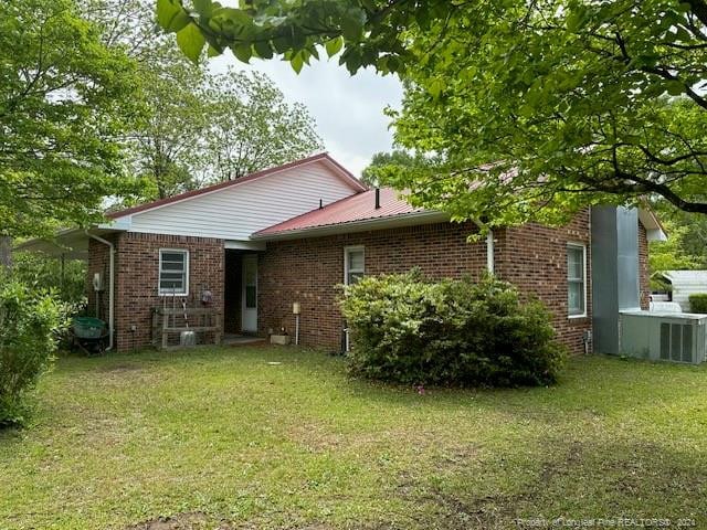 rear view of house featuring central AC and a yard