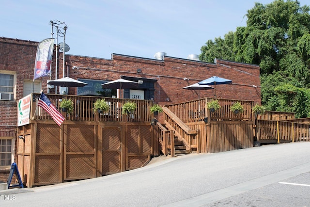 exterior space featuring brick siding, a wooden deck, and stairs