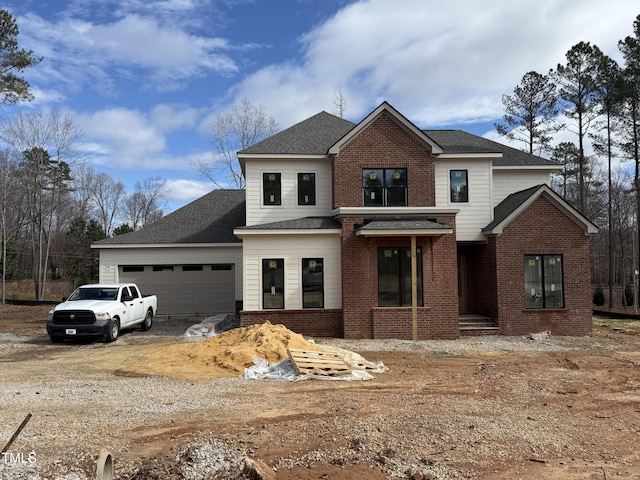 traditional-style house with dirt driveway, brick siding, and an attached garage