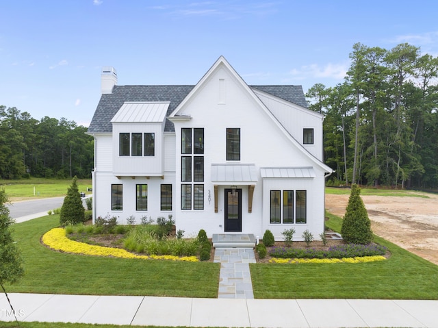 3401 Makers Cir, Raleigh, NC 27612 - modern inspired farmhouse featuring a standing seam roof, a chimney, a front lawn, a metal roof, and a shingled roof