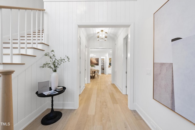 hallway with a chandelier and light hardwood / wood-style floors