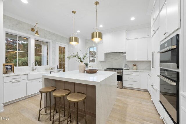 kitchen featuring sink, stainless steel stove, white cabinetry, a center island, and custom range hood